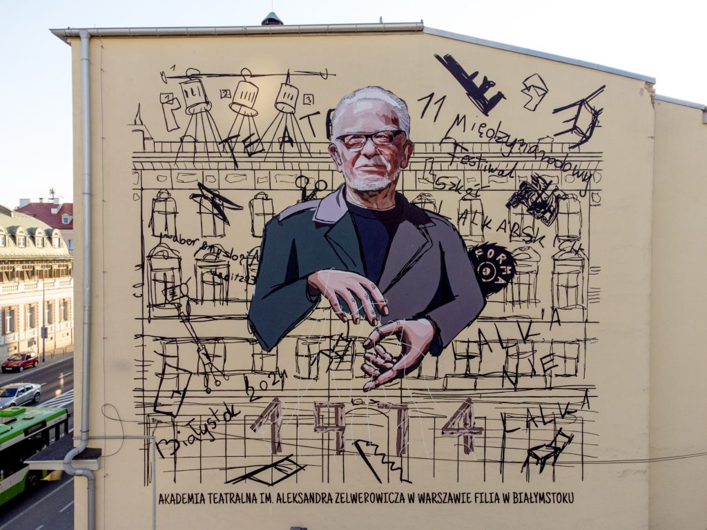 Mural na szczytowej ścianie budynku przedstawiający popiersie prof. Krzysztofa Raua ze sznurkami od marionetki założonymi na dłonie. Sznurki przyczepione są do daty 1974 ułożonej ze spinaczy. W tle niedbały rysunek fasady siedziby Akademii oraz przedmioty i symbole związane z teatrem lalkowym i Festiwalem LALKANIELALKA.