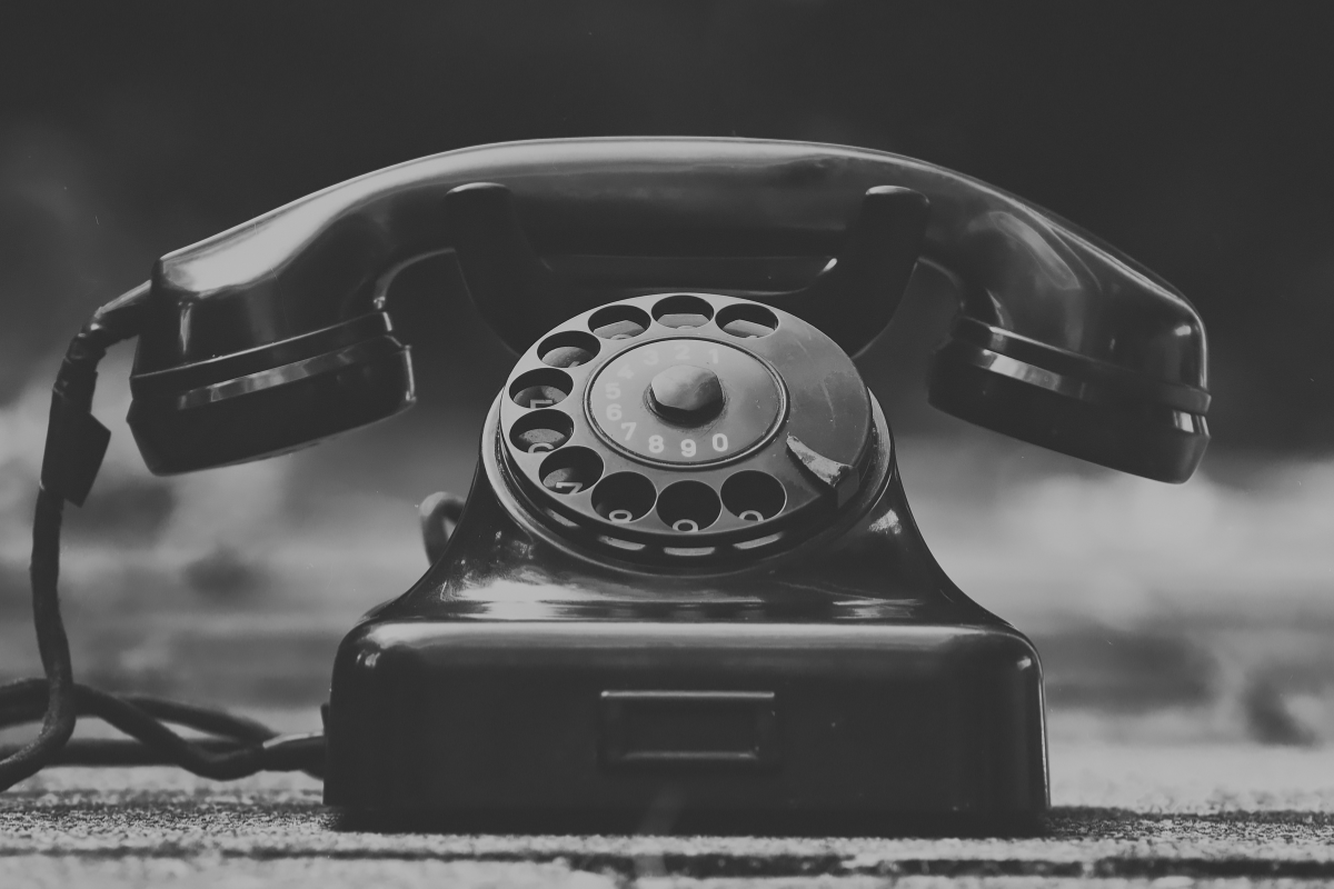 Czarno-białe zdjęcie starego aparatu telefonicznego z tarczą.