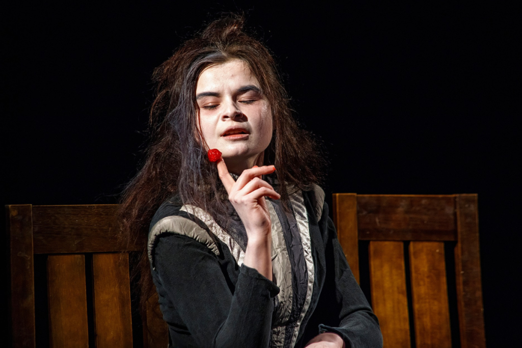 Kadr ze spektaklu: studentka ucharakteryzowana na Balladynę z maliną wetkniętą na palec.