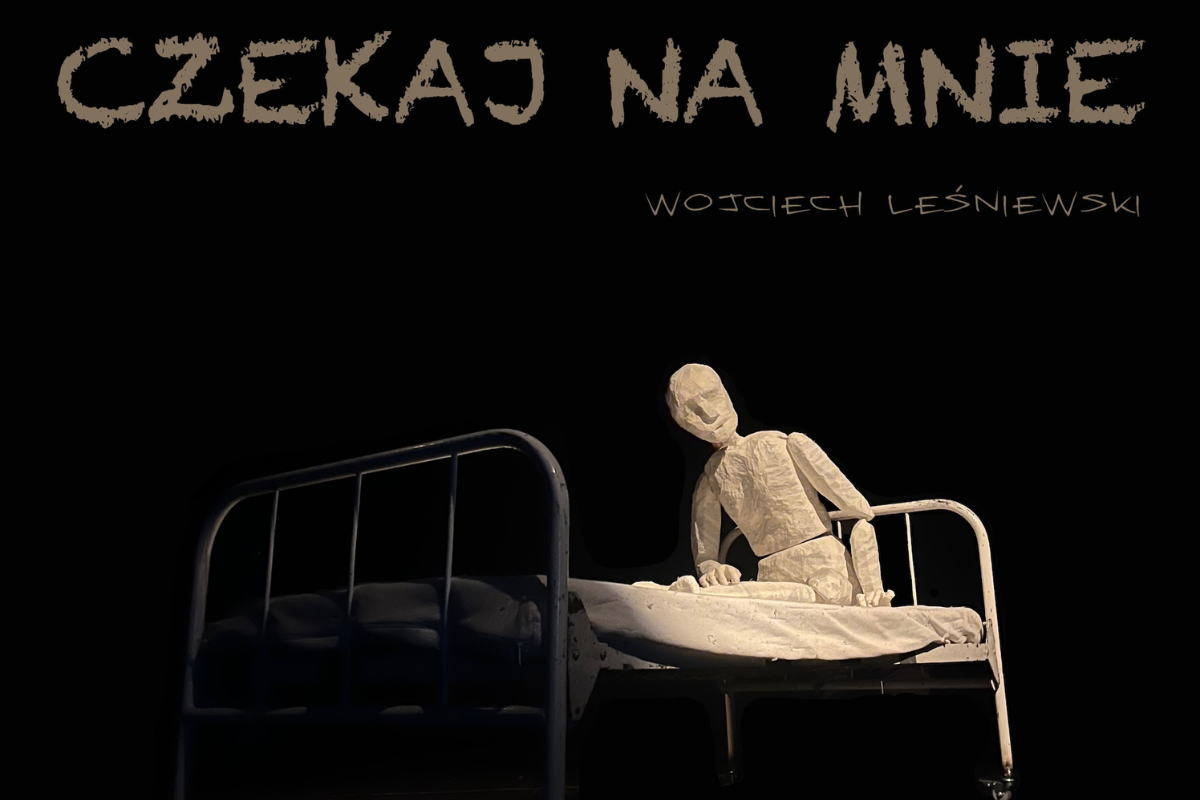 Goła lalka teatralna siedząca na metalowym łóżku starego typu. U góry napis: Czekaj na mnie.