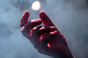 Dłoń oblepiona cząstkami malin stara się schwycić jaśniejący kolisty kształt.