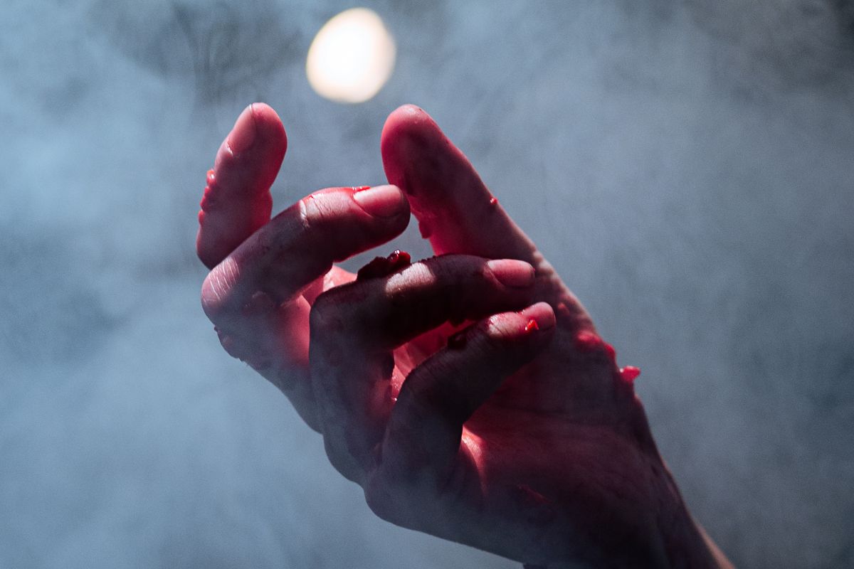 Dłoń oblepiona cząstkami malin stara się schwycić jaśniejący kolisty kształt.