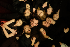 Zrobione z góry zdjęcie grupy studentów leżących na podłodze z głowami skierowanymi do centrum.