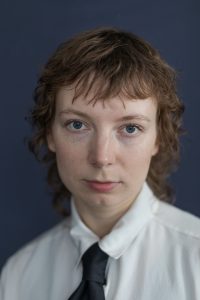 Portret Aleksandry Gosławskiej w białej koszuli z krawatem.