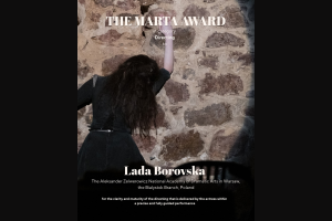 Zdjęcie z występu: postać młodej kobiety w czarnej sukni widziana od tyłu na tle kamiennej ściany.